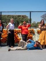 Registrar staff posing in front of Pitzer sign made of flowers