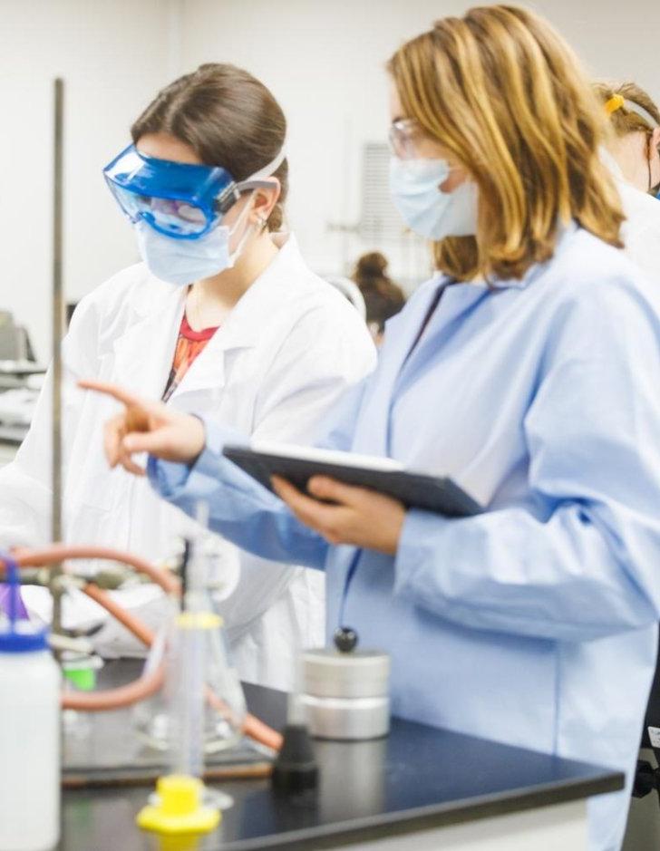 A professor explains an experiment to students in a chemistry lab